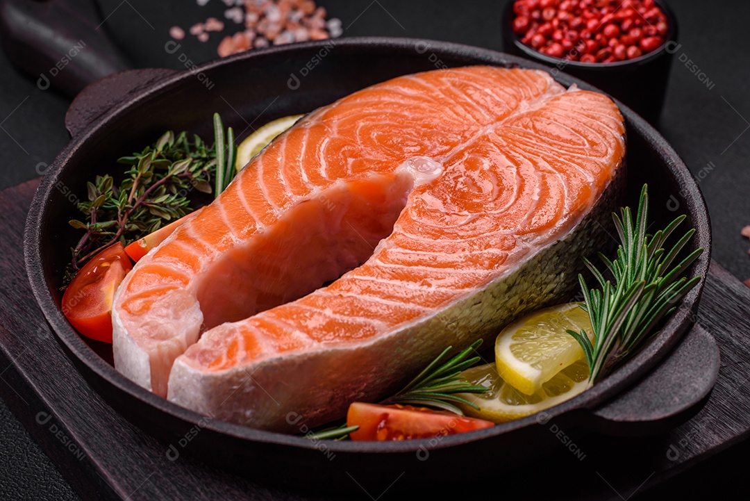 Bife de peixe vermelho cru fresco com especiarias e ervas sobre um fundo escuro de concreto