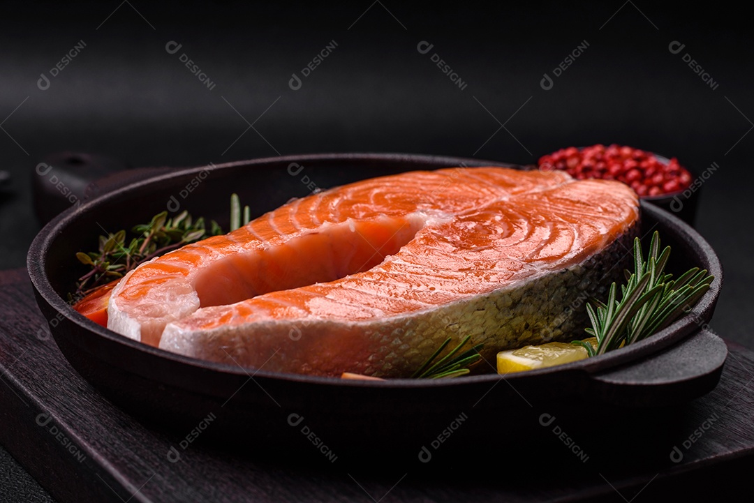 Bife de peixe vermelho cru fresco com especiarias e ervas sobre um fundo escuro de concreto