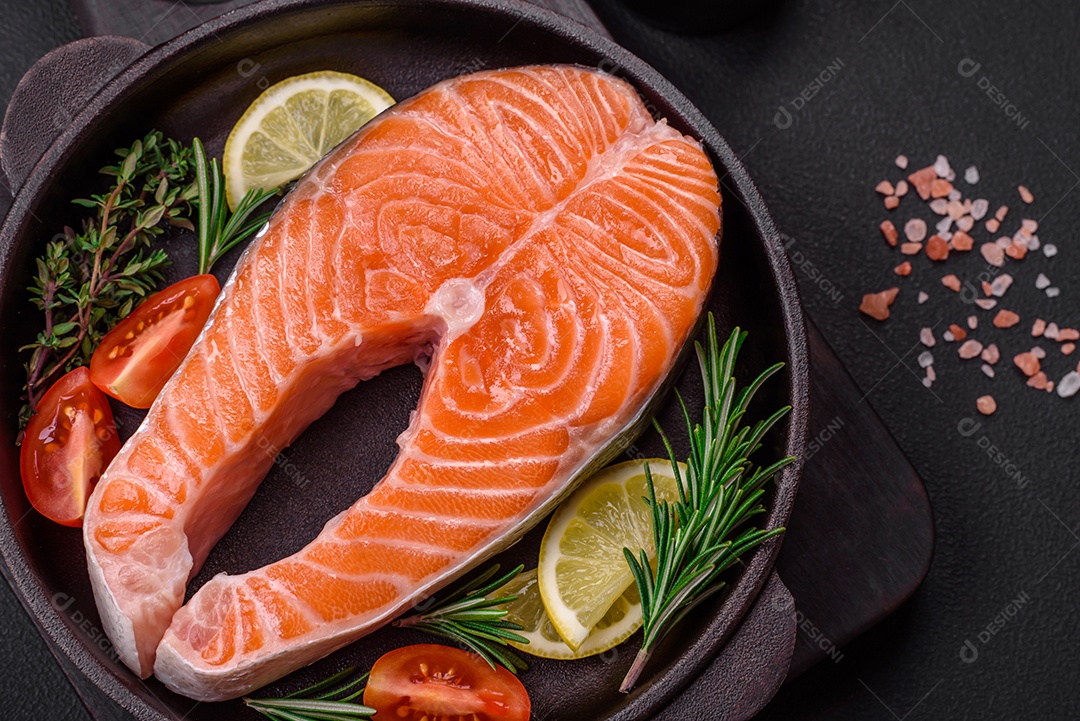 Bife de peixe vermelho cru fresco com especiarias e ervas sobre um fundo escuro de concreto