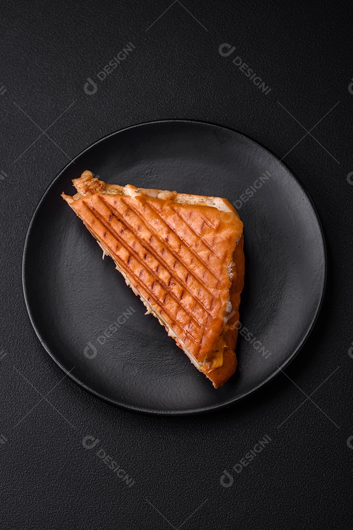 Delicioso sanduíche crocante com peito de frango, tomate, ketchup e especiarias em um fundo escuro de concreto