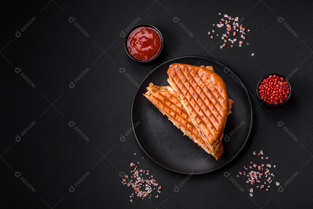 Delicioso sanduíche crocante com peito de frango, tomate, ketchup e especiarias em um fundo escuro de concreto