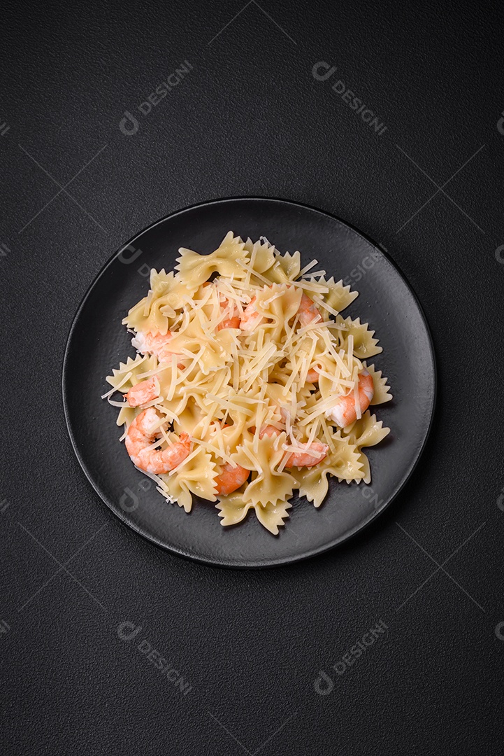 Deliciosa massa farfalle com camarão lagostim com molho cremoso e queijo sobre fundo escuro de concreto
