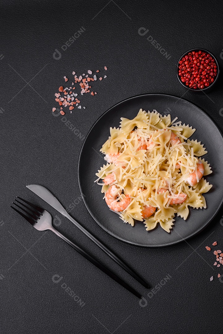 Deliciosa massa farfalle com camarão lagostim com molho cremoso e queijo sobre fundo escuro de concreto