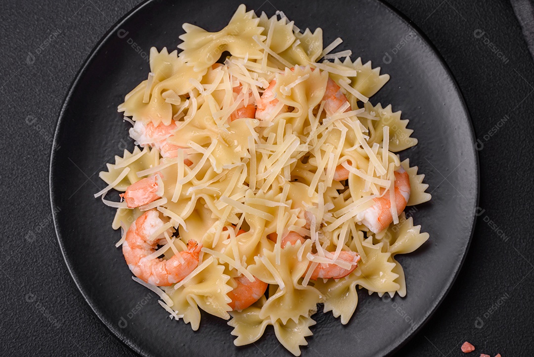 Deliciosa massa farfalle com camarão lagostim com molho cremoso e queijo sobre fundo escuro de concreto