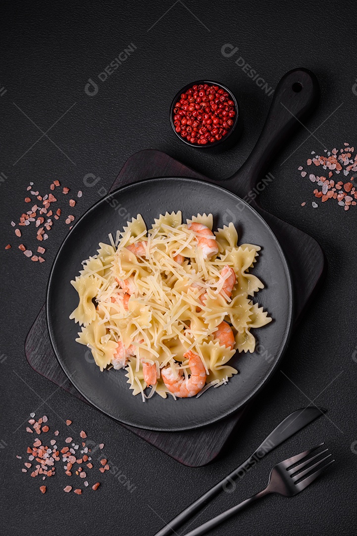 Deliciosa massa farfalle com camarão lagostim com molho cremoso e queijo sobre fundo escuro de concreto