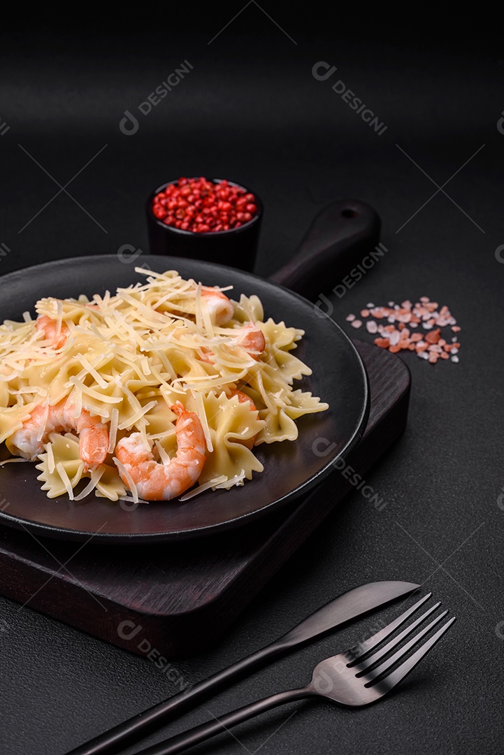 Deliciosa massa farfalle com camarão lagostim com molho cremoso e queijo sobre fundo escuro de concreto