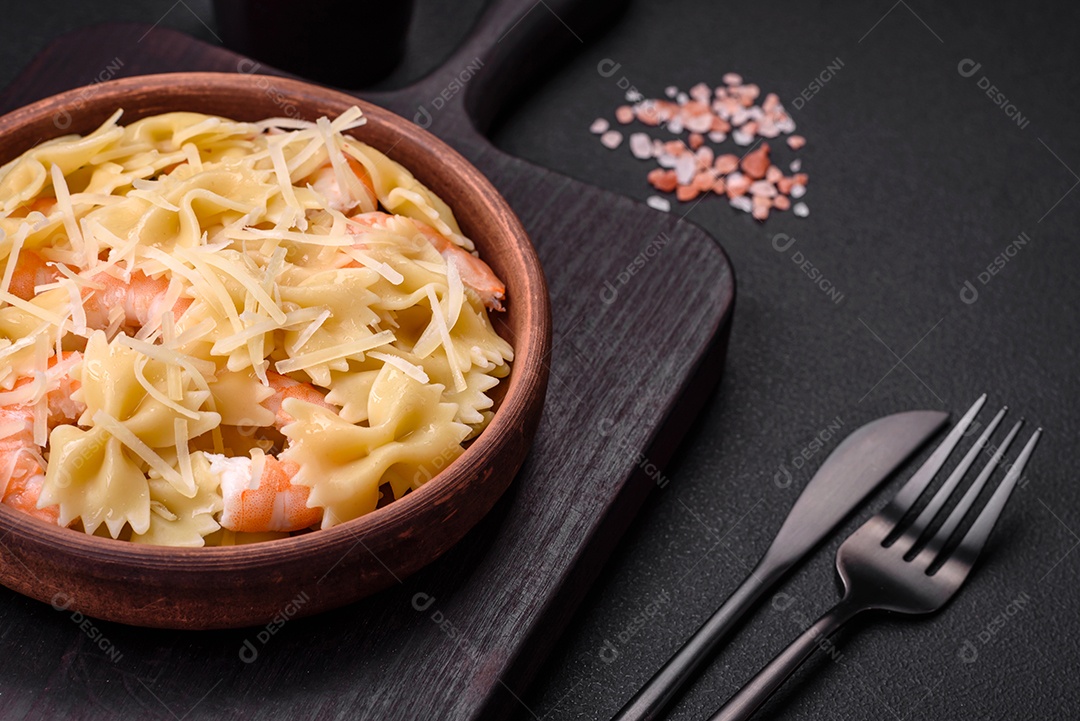 Deliciosa massa farfalle com camarão lagostim com molho cremoso e queijo sobre fundo escuro de concreto