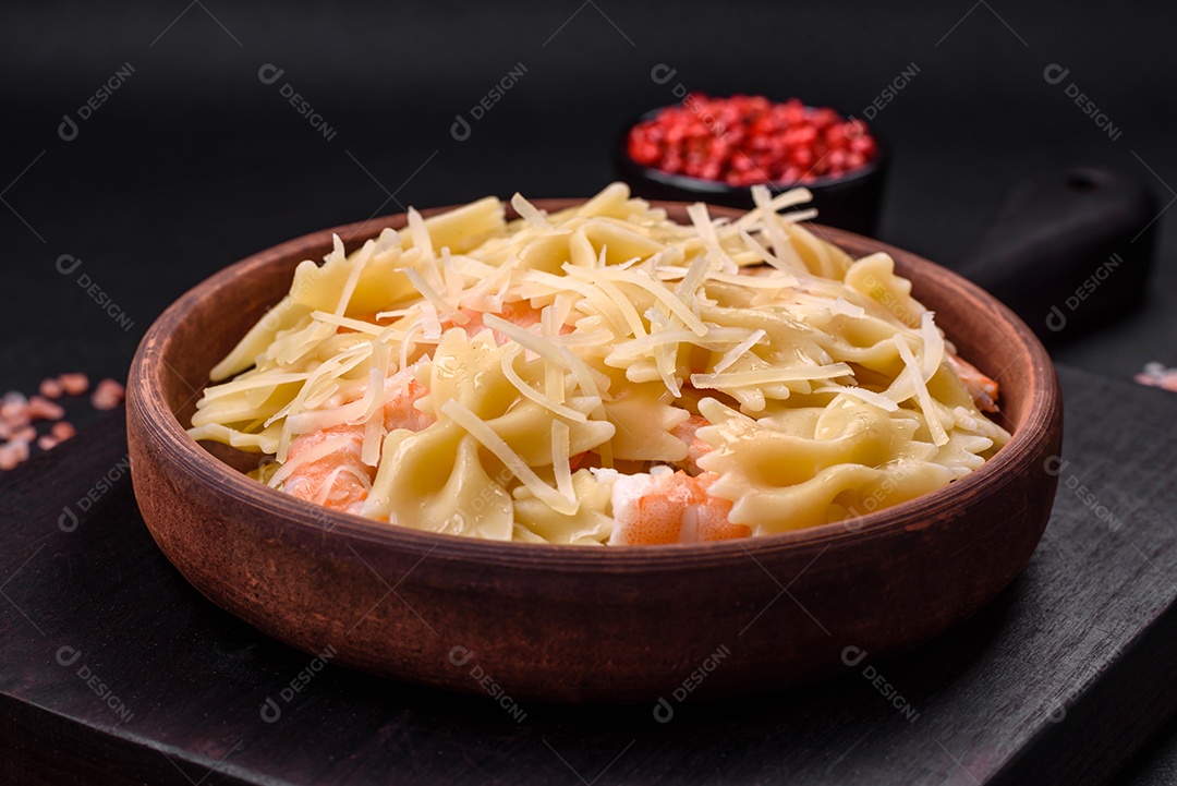 Deliciosa massa farfalle com camarão lagostim com molho cremoso e queijo sobre fundo escuro de concreto