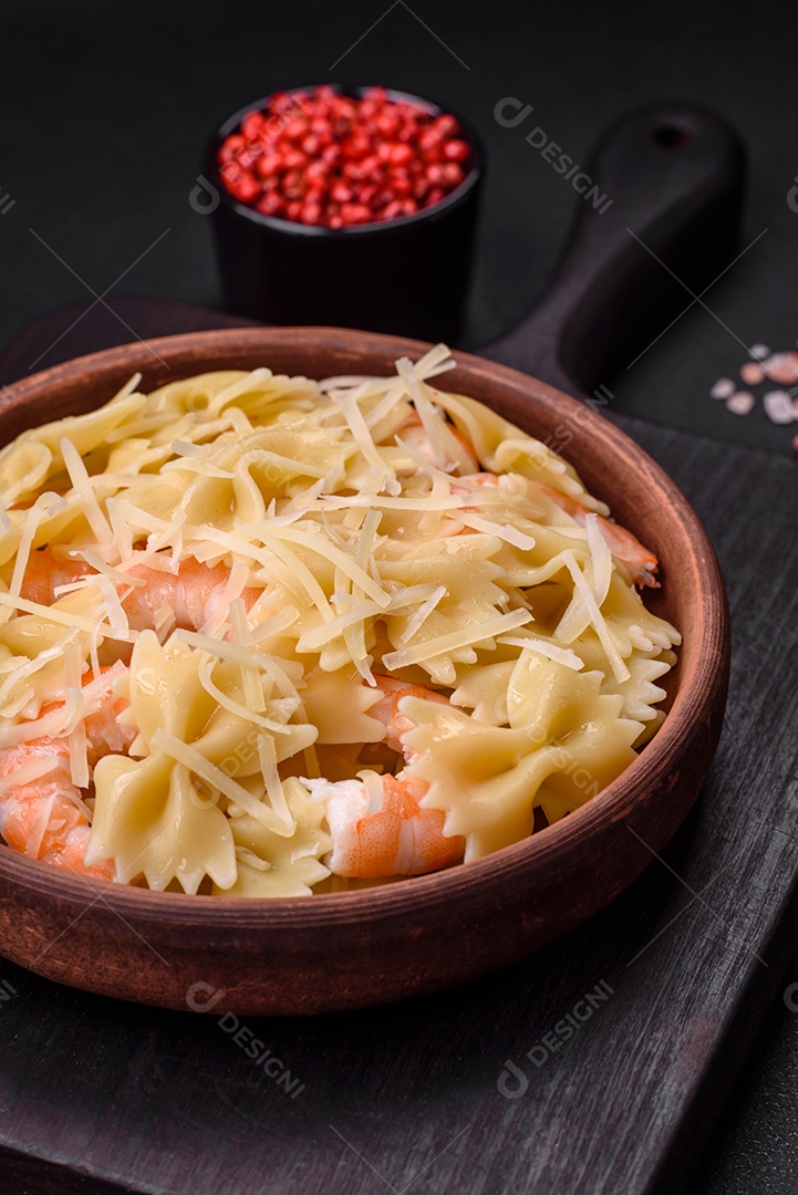 Deliciosa massa farfalle com camarão lagostim com molho cremoso e queijo sobre fundo escuro de concreto