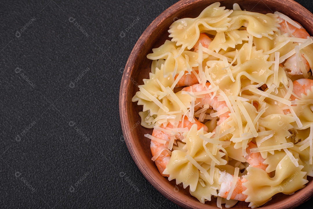 Deliciosa massa farfalle com camarão lagostim com molho cremoso e queijo sobre fundo escuro de concreto