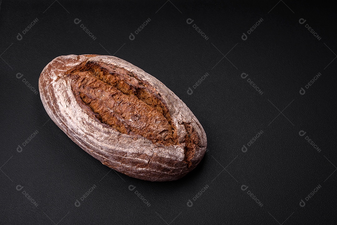 Delicioso pão de massa fermentada marrom fresco com grãos em fundo escuro de concreto