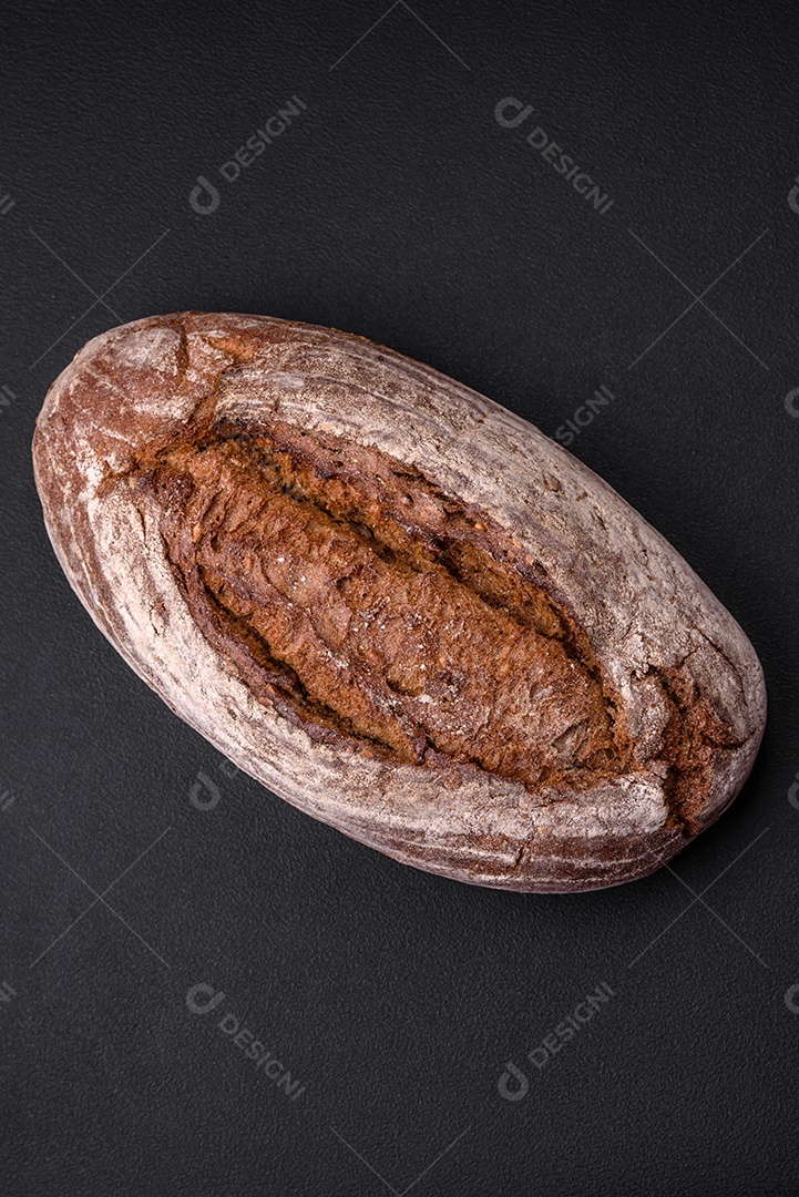 Delicioso pão de massa fermentada marrom fresco com grãos em fundo escuro de concreto