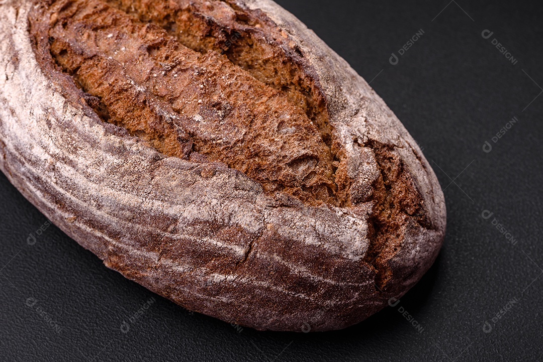 Delicioso pão de massa fermentada marrom fresco com grãos em fundo escuro de concreto