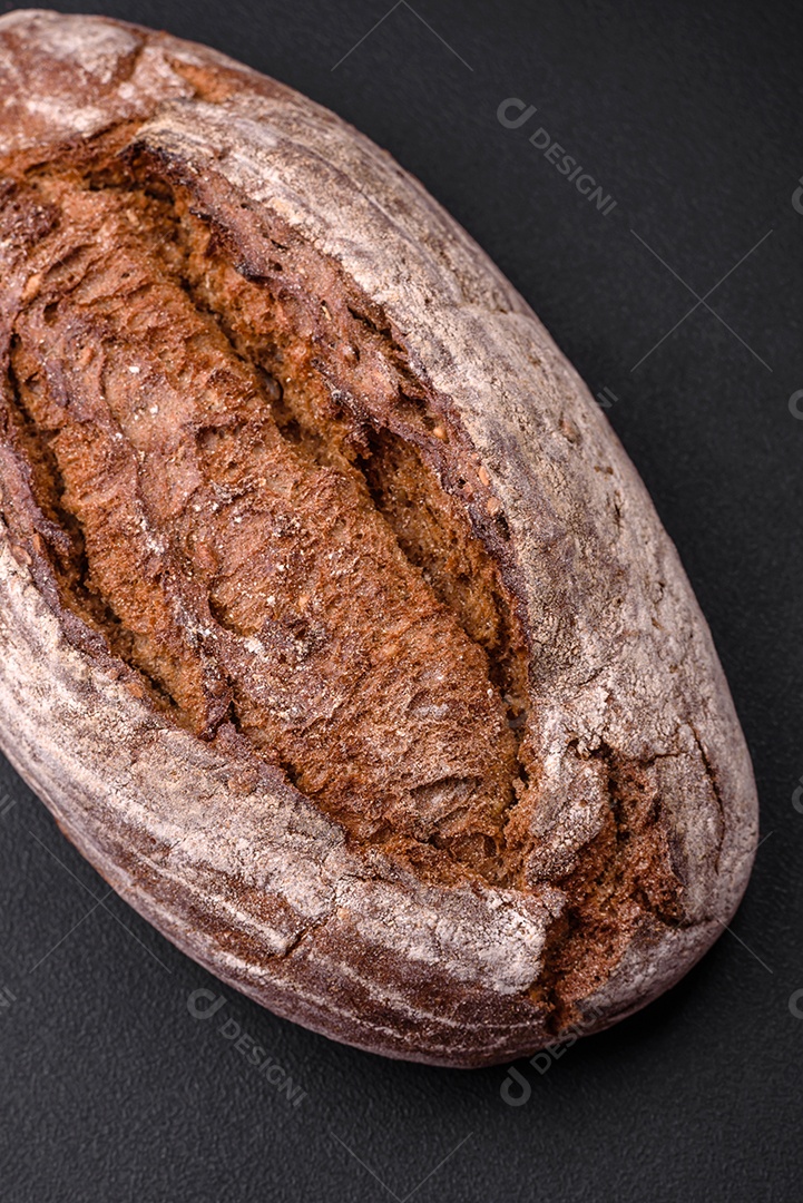 Delicioso pão de massa fermentada marrom fresco com grãos em fundo escuro de concreto