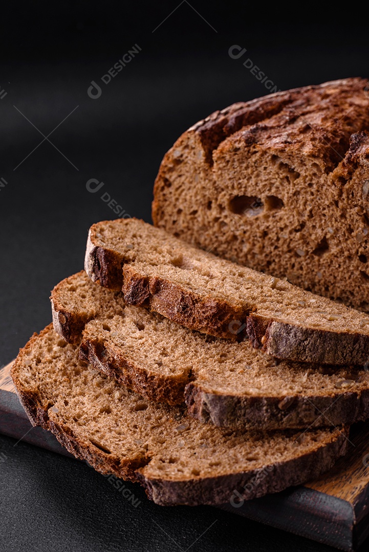 Delicioso pão de massa fermentada marrom fresco com grãos em fundo escuro de concreto