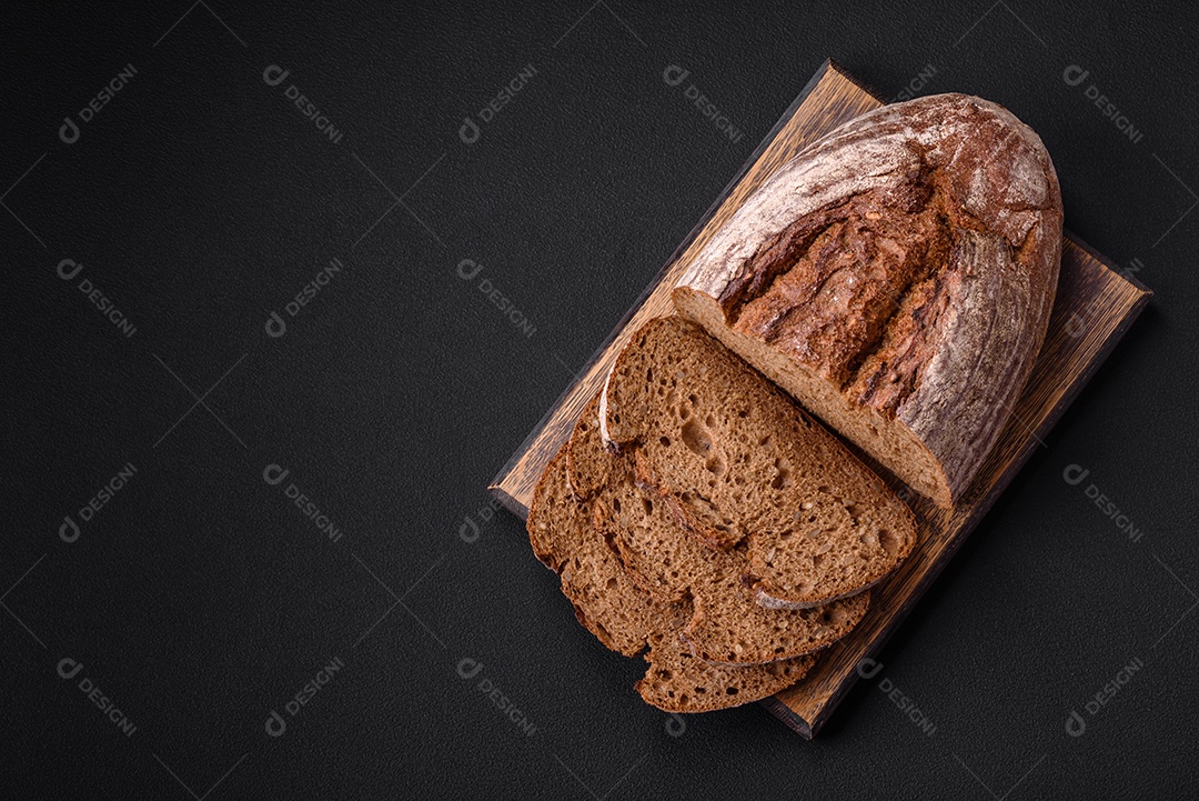 Delicioso pão de massa fermentada marrom fresco com grãos em fundo escuro de concreto