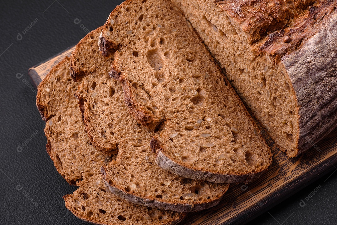 Delicioso pão de massa fermentada marrom fresco com grãos em fundo escuro de concreto