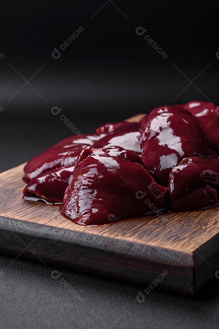 Frango cru fresco, peru ou fígado de pato com sal, especiarias e ervas sobre um fundo escuro de concreto