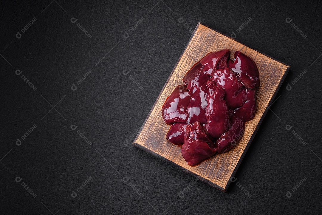 Frango cru fresco, peru ou fígado de pato com sal, especiarias e ervas sobre um fundo escuro de concreto