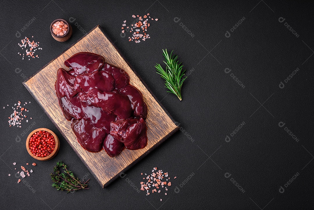 Frango cru fresco, peru ou fígado de pato com sal, especiarias e ervas sobre um fundo escuro de concreto