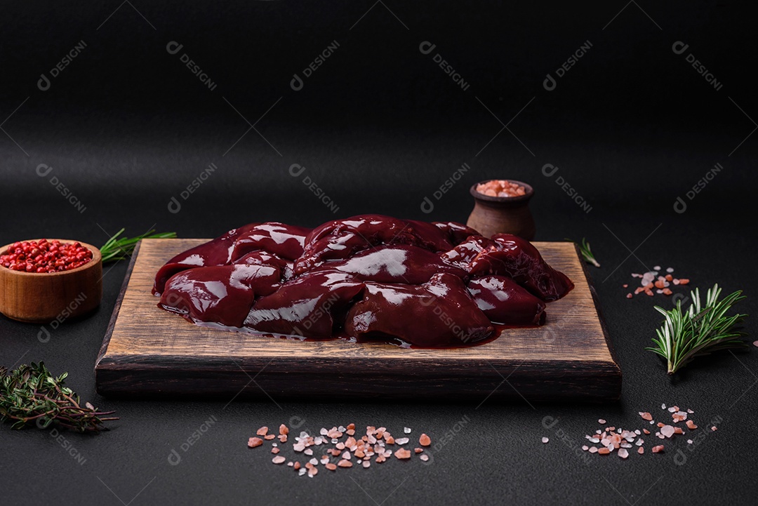 Frango cru fresco, peru ou fígado de pato com sal, especiarias e ervas sobre um fundo escuro de concreto