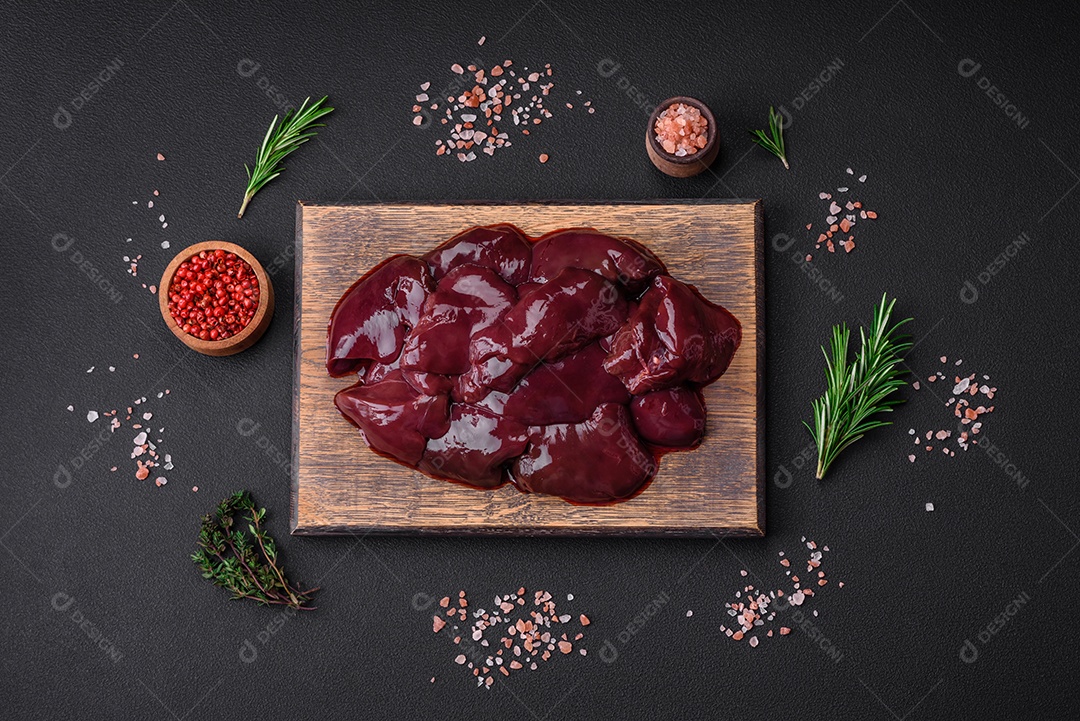 Frango cru fresco, peru ou fígado de pato com sal, especiarias e ervas sobre um fundo escuro de concreto