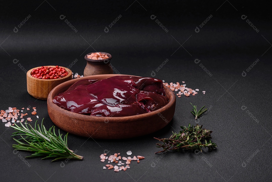 Frango cru fresco, peru ou fígado de pato com sal, especiarias e ervas sobre um fundo escuro de concreto