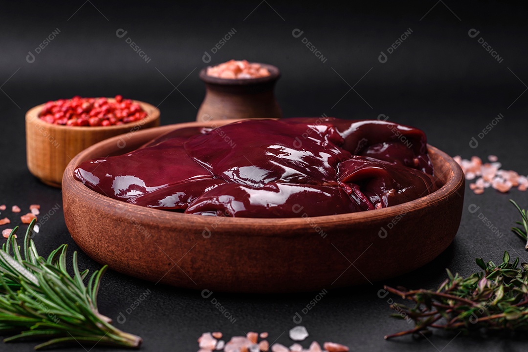 Frango cru fresco, peru ou fígado de pato com sal, especiarias e ervas sobre um fundo escuro de concreto