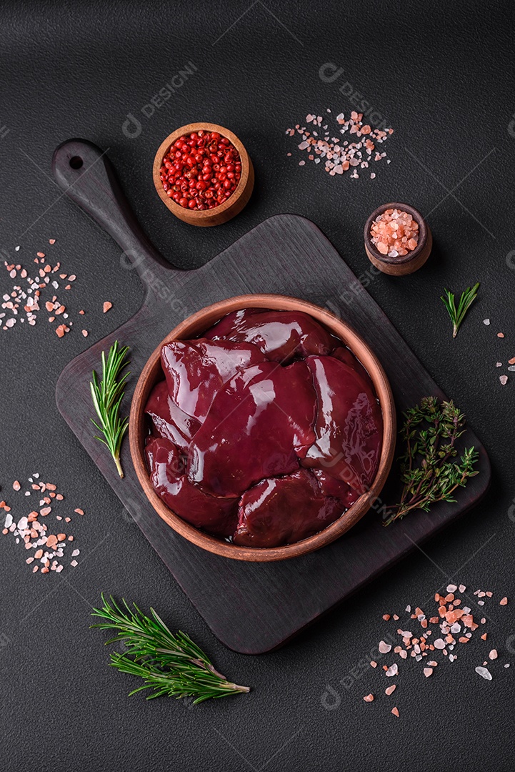 Fígado de pato com sal, especiarias e ervas sobre um fundo escuro de concreto