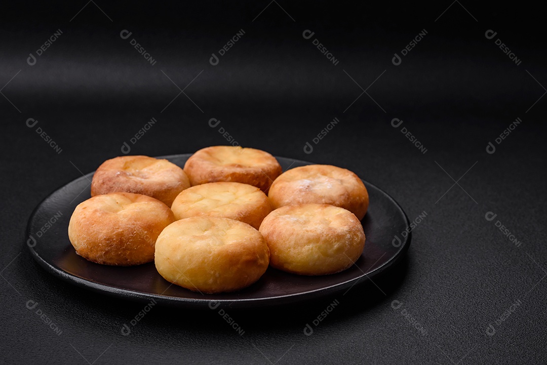 Deliciosos cheesecakes frescos com passas e baunilha em uma placa de cerâmica preta sobre um fundo escuro de concreto