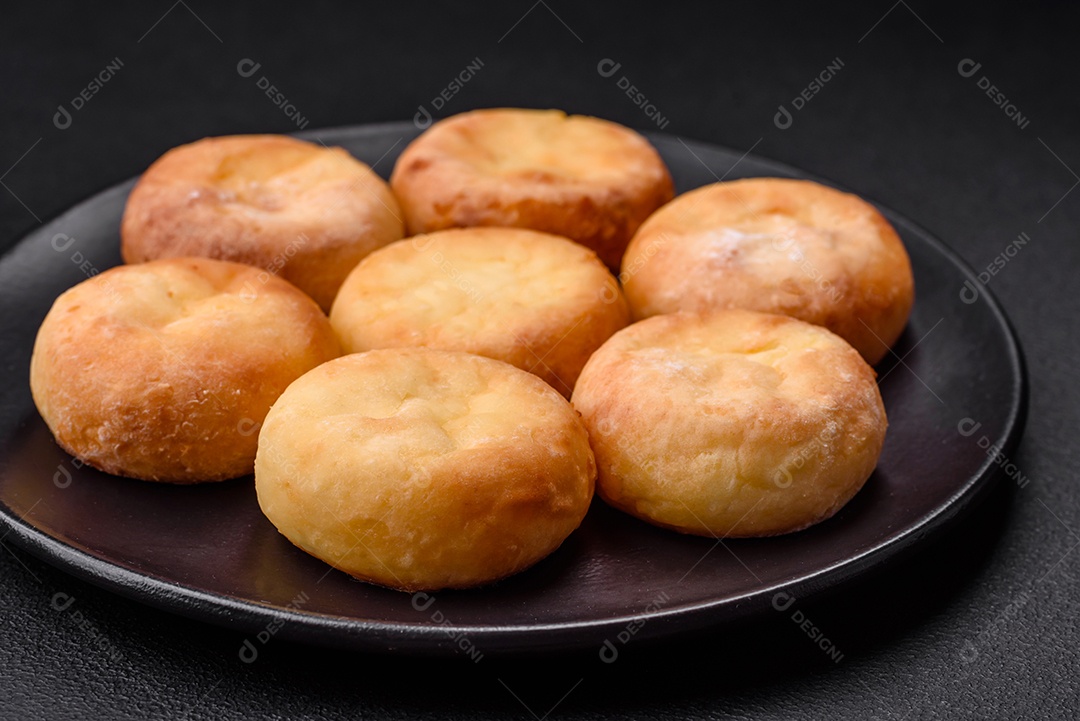 Deliciosos cheesecakes frescos com passas e baunilha em uma placa de cerâmica preta sobre um fundo escuro de concreto