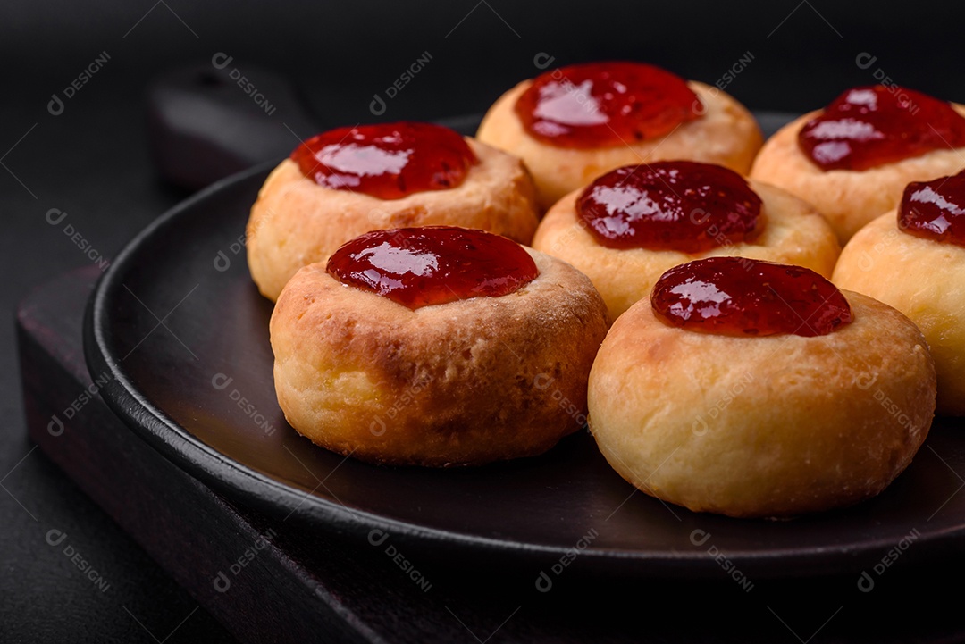 Deliciosos cheesecakes frescos com passas e baunilha em uma placa de cerâmica preta sobre um fundo escuro de concreto