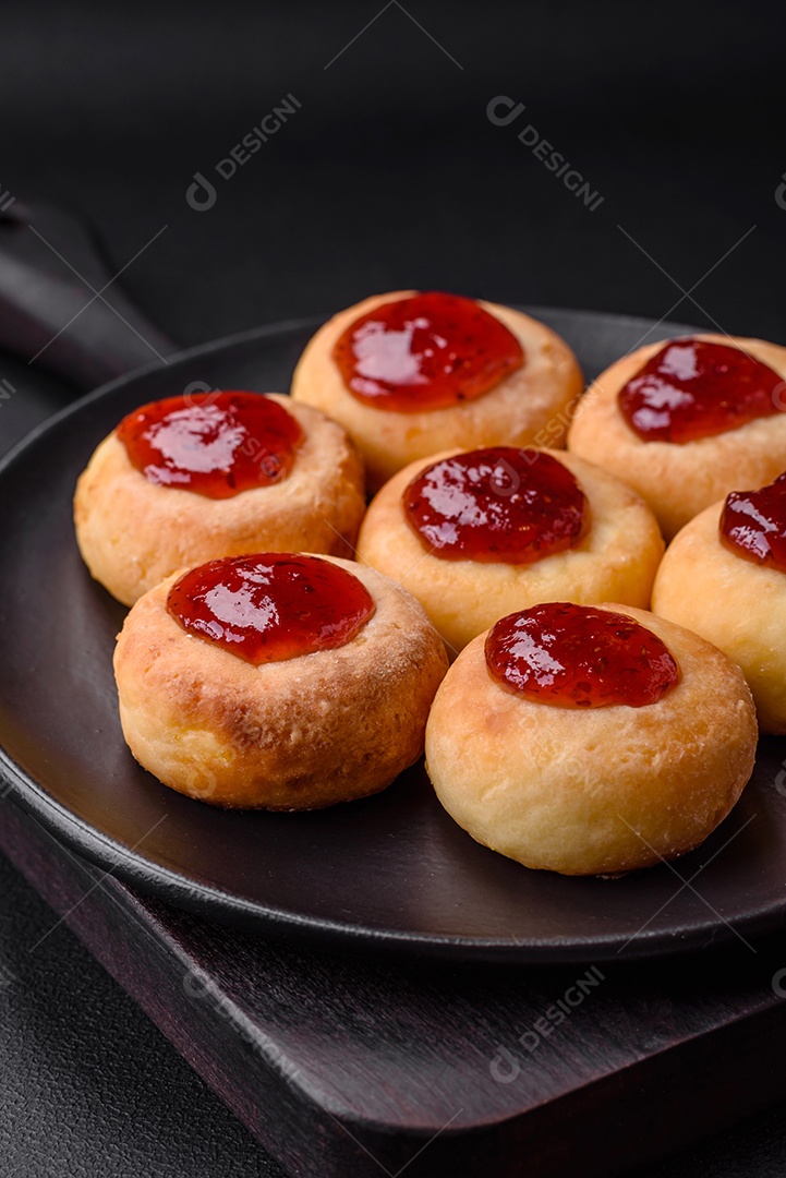 Deliciosos cheesecakes frescos com passas e baunilha em uma placa de cerâmica preta sobre um fundo escuro de concreto