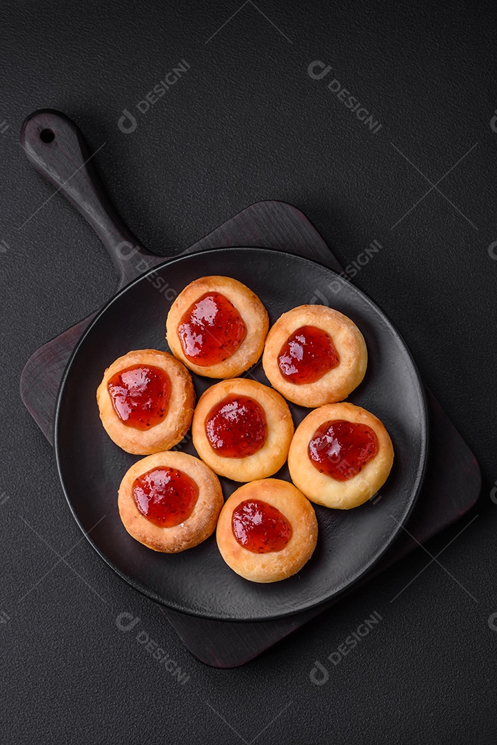 Deliciosos cheesecakes frescos com passas e baunilha em uma placa de cerâmica preta sobre um fundo escuro de concreto