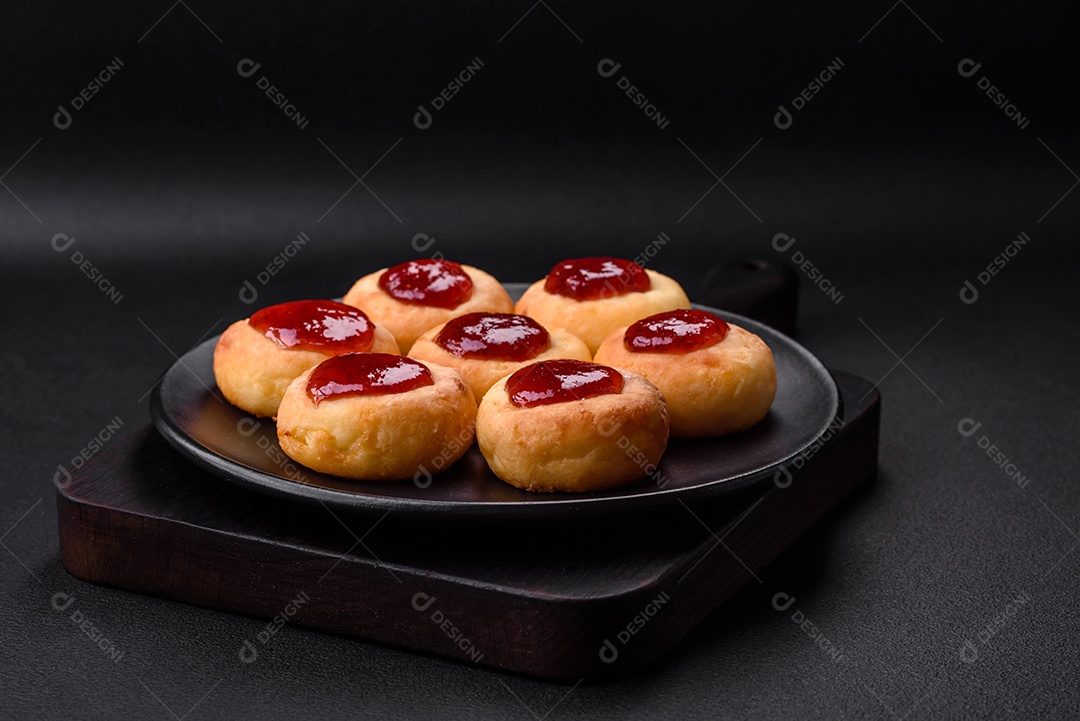 Deliciosos cheesecakes frescos com passas e baunilha em uma placa de cerâmica preta sobre um fundo escuro de concreto
