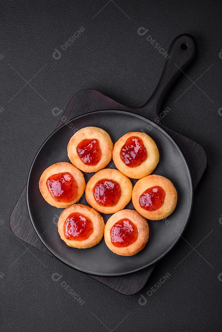 Deliciosos cheesecakes frescos com passas e baunilha em uma placa de cerâmica preta sobre um fundo escuro de concreto