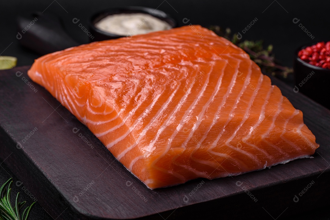 Filé de peixe vermelho fresco e saboroso com especiarias e ervas sobre um fundo escuro de concreto