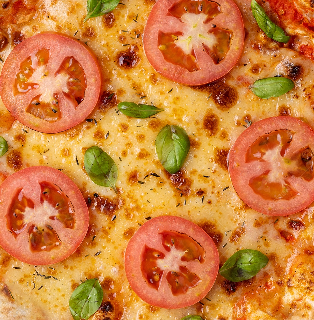 Closeup de pizza margherita com tomate e manjericão.