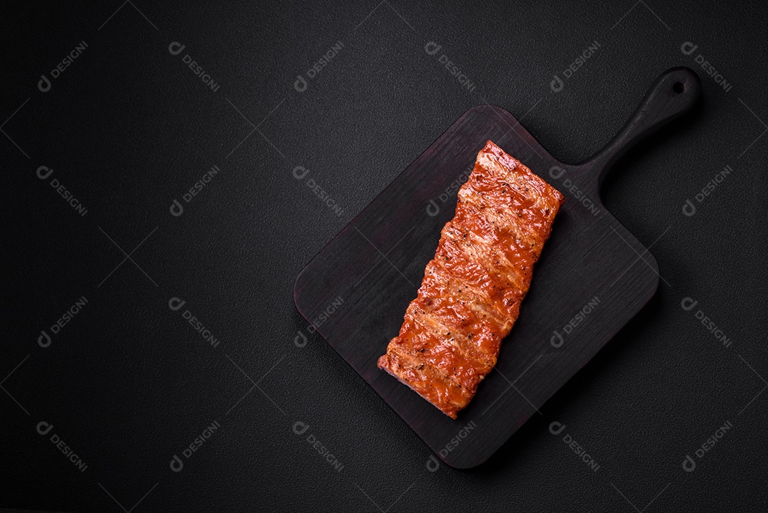 Deliciosas costelas frescas grelhadas ou defumadas com sal, especiarias e ervas em fundo escuro de concreto