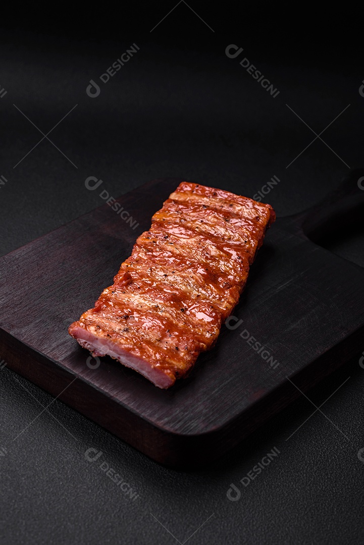 Deliciosas costelas frescas grelhadas ou defumadas com sal, especiarias e ervas em fundo escuro de concreto