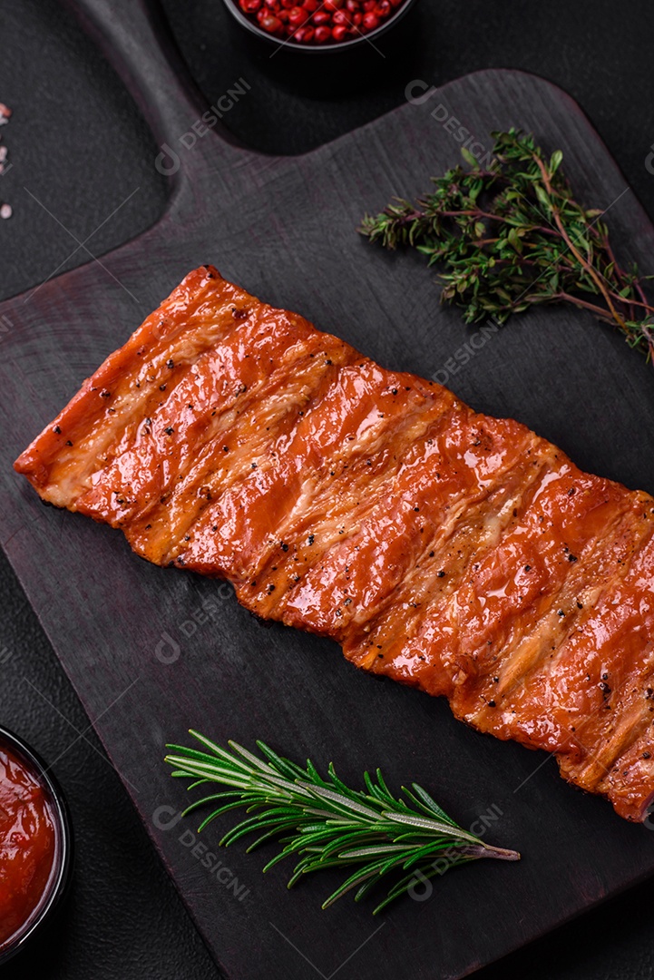 Deliciosas costelas frescas grelhadas ou defumadas com sal, especiarias e ervas em fundo escuro de concreto