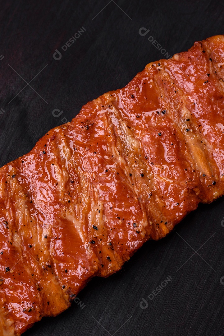 Deliciosas costelas frescas grelhadas ou defumadas com sal, especiarias e ervas em fundo escuro de concreto