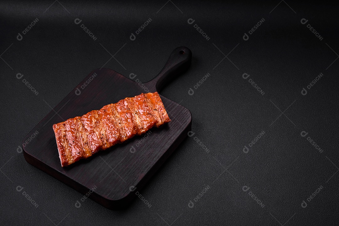 Deliciosas costelas frescas grelhadas ou defumadas com sal, especiarias e ervas em fundo escuro de concreto
