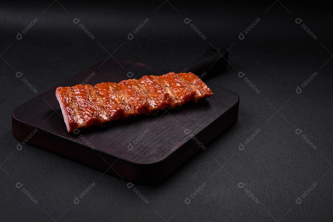 Deliciosas costelas frescas grelhadas ou defumadas com sal, especiarias e ervas em fundo escuro de concreto