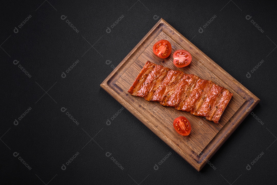 Deliciosas costelas frescas grelhadas ou defumadas com sal, especiarias e ervas em fundo escuro de concreto