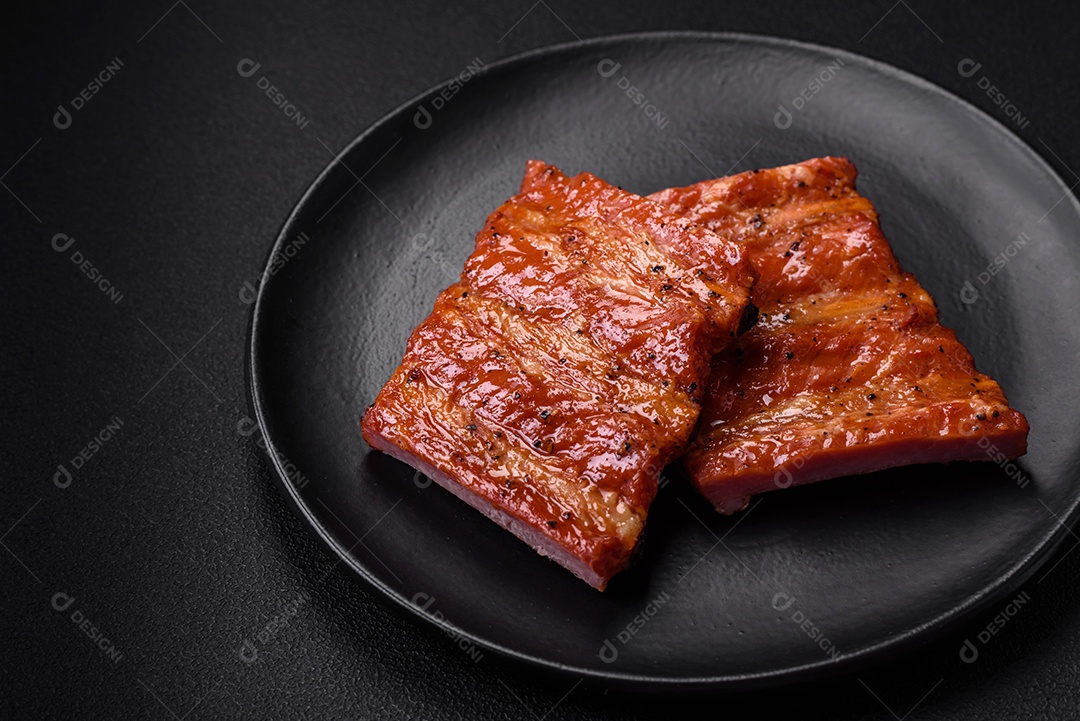 Deliciosas costelas frescas grelhadas ou defumadas com sal, especiarias e ervas em fundo escuro de concreto