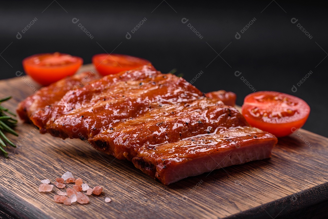 Deliciosas costelas frescas grelhadas ou defumadas com sal, especiarias e ervas em fundo escuro de concreto