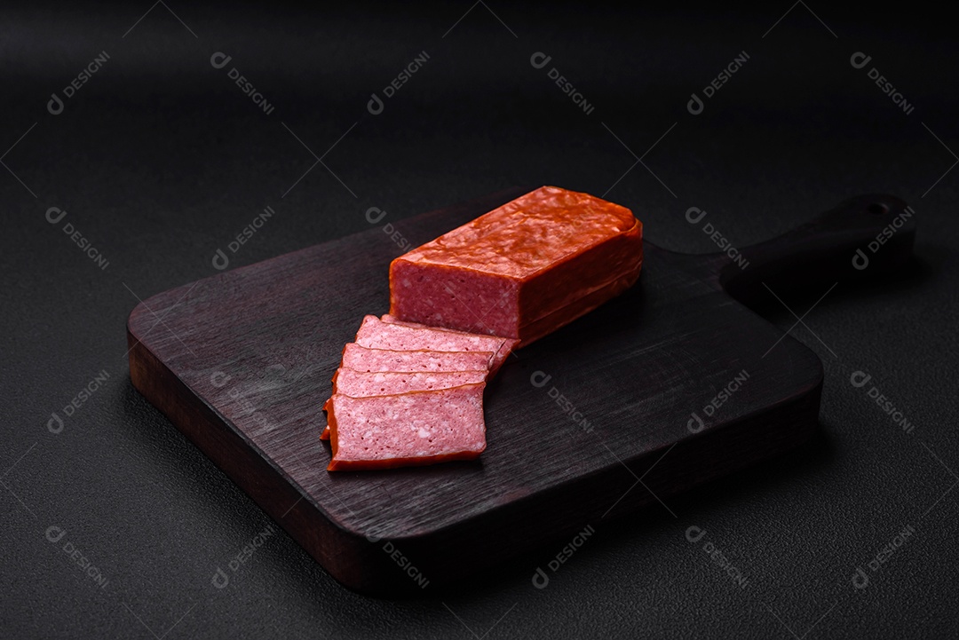 Delicioso salame de salsicha fresca com sal, tomate e especiarias sobre um fundo escuro de concreto