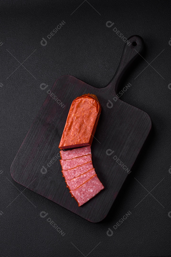 Delicioso salame de salsicha fresca com sal, tomate e especiarias sobre um fundo escuro de concreto