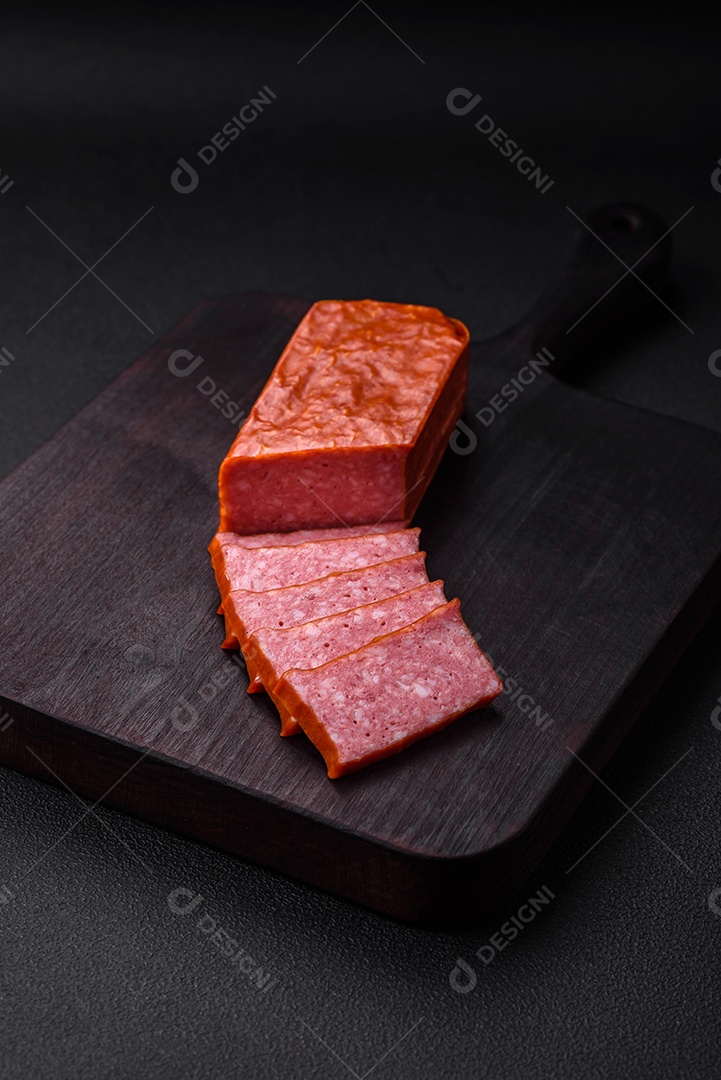 Delicioso salame de salsicha fresca com sal, tomate e especiarias sobre um fundo escuro de concreto
